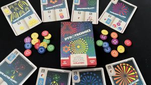A box of the Pyrotechnics board game surrounded by cards and tokens. Courtesy of Gaming Trend.