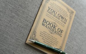The Book of Wandering (a self-traveling journal) with a mechanical pencil.