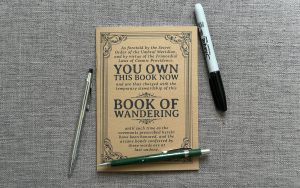 The Book of Wandering (a self-traveling journal) with a mechanical pencil, a pen and a Sharpie marker.