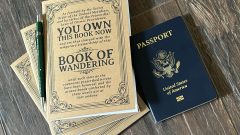 The Book of Wandering, The Enchanted Self-Traveling Journal, shown here with three copies, a mechanical pencil and a passport.