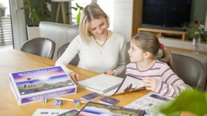 A woman and a girl sitting together playing the solo board game Witchbound.